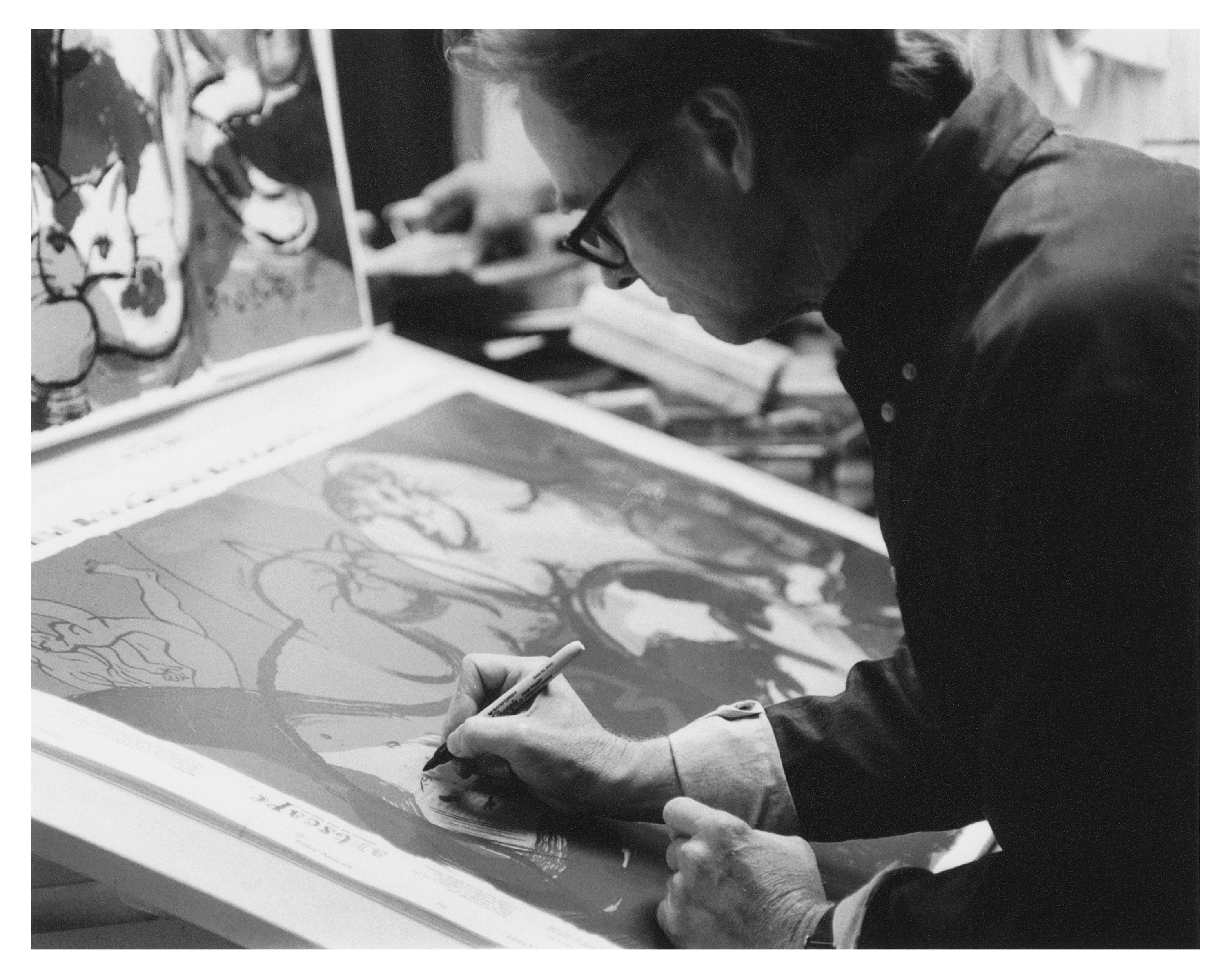 Black and white image of man drawing on window film with pen.