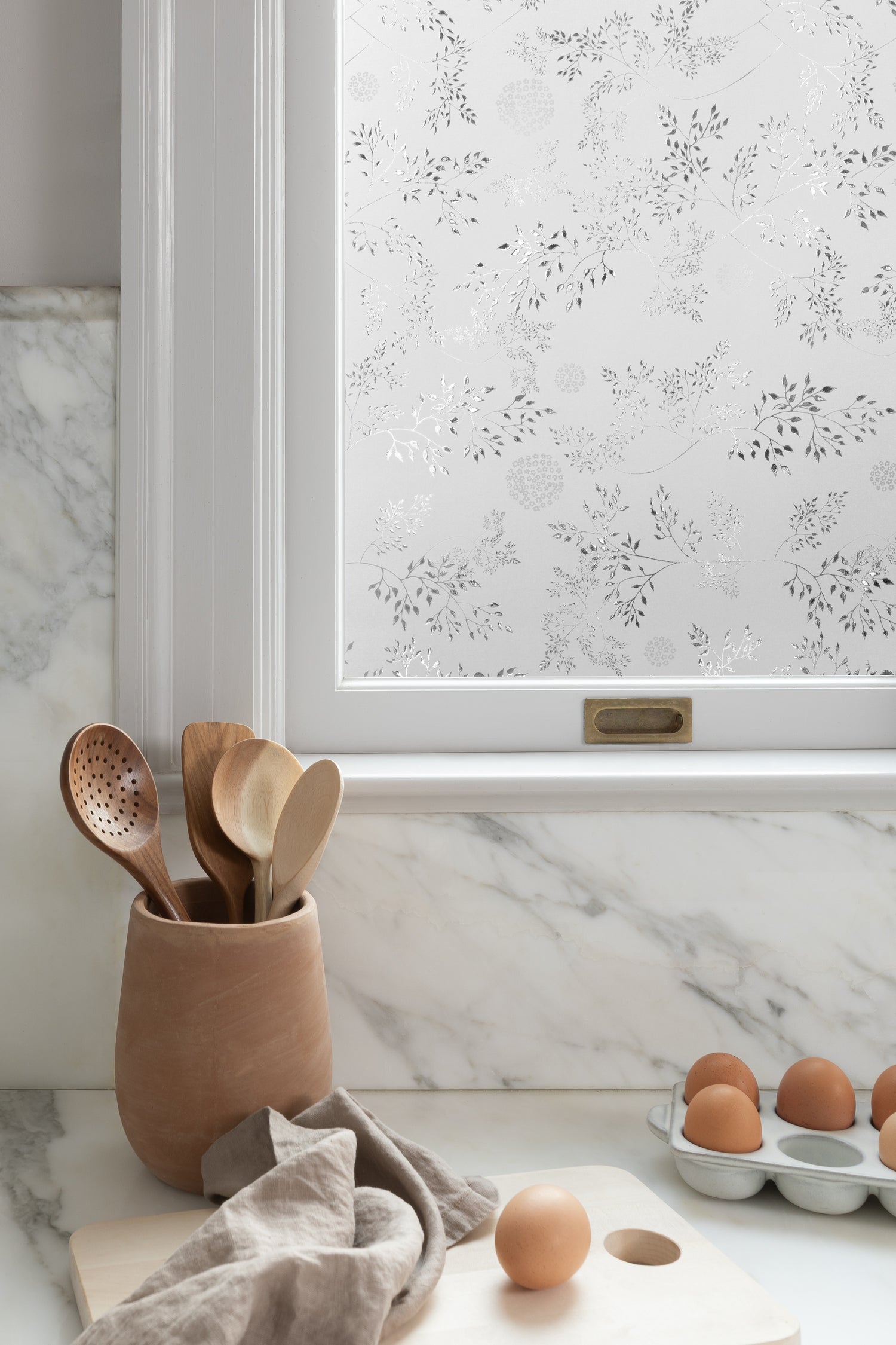 Corner of window covered in window film with eggs and spoons on counter.