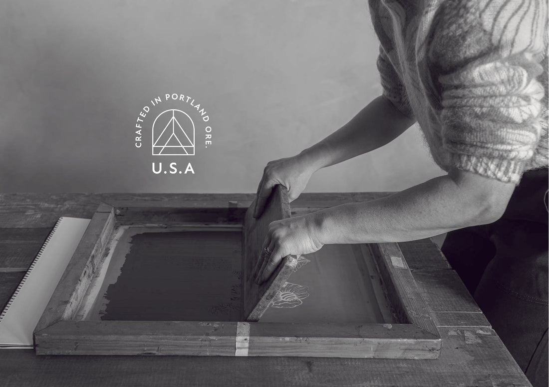 Monochrome photo of a woman using a wooden block for screen-printing, with 'Crafted in Portland, Ore. U.S.A.' text next to the Artscape logo in the top left.