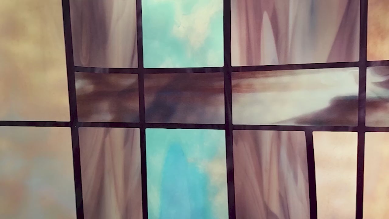 Video moving over close-up of a decorative privacy window film with with neutral colors paired with bright blues in a geometric design.